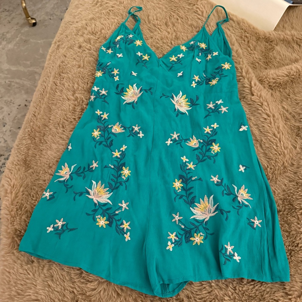 teal-colored romper featuring spaghetti straps and intricate white and yellow